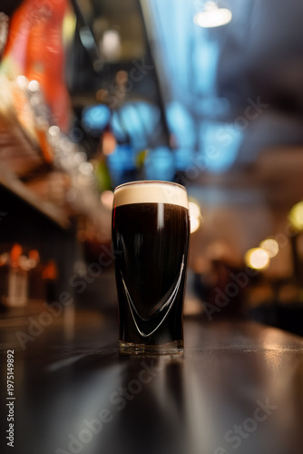 Tableau sur toile Dark stout beer in glass with creamy foam on bar counter
Draft dark beer pouring