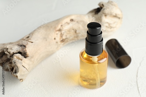 Bottle of cosmetic product, cap and snag on light textured table, closeup