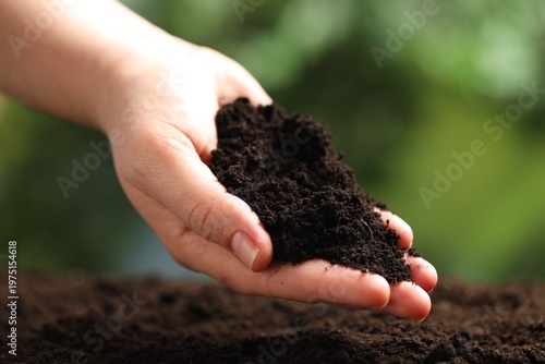 Woman with fresh soil on blurred background, closeup