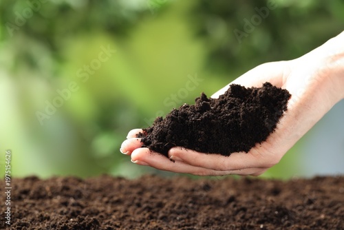 Woman with fresh soil on blurred background, closeup