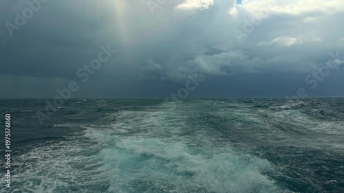 Wide Angle View From A Ferry Deck Showing White Water Foam Trails On Churning Blue Ocean Waves. Dramatic Dark Storm Clouds Over The Horizon Create A Powerful And Intense Nautical Scene. 