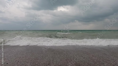 Spring seaside with waves under cloudy sky
