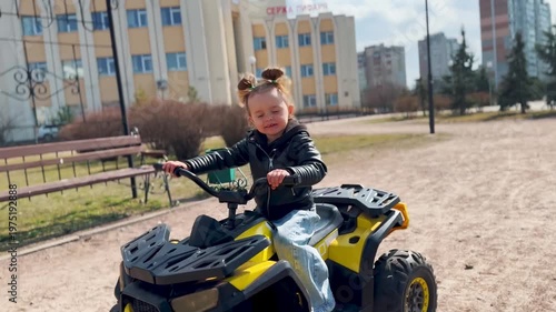 Kid driving a small electric quad bike outdoors. Close-up action shot of child riding battery powered vehicle. Concept of active play, mobility and childhood fun