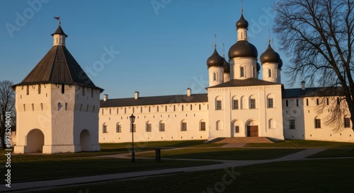 Ancient white stone structure with multiple domes, towers, and surrounding walls under a blue sky