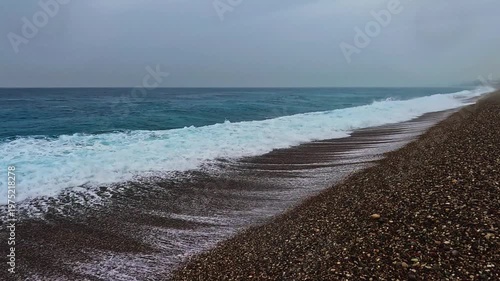 Spring seaside with waves under cloudy sky