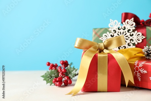 Pile of many gift boxes with decor on light table against blue background, closeup with space for text. Merry Christmas and Happy New Year