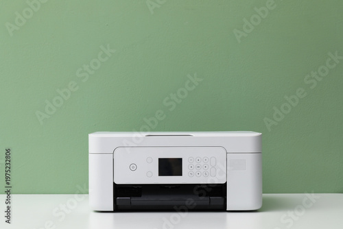 One printer on white table near green wall