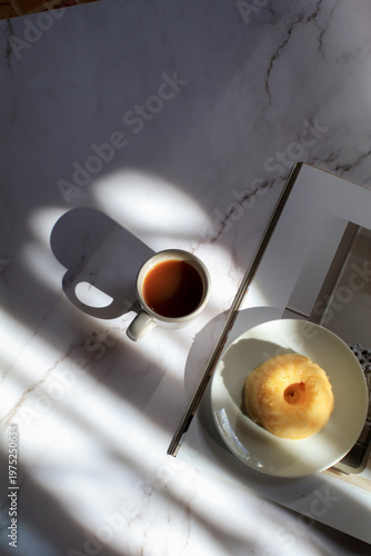 Lemon pound cake and hot coffee under sunlight and shadow on white background. Modern minimal elegant aesthetic.