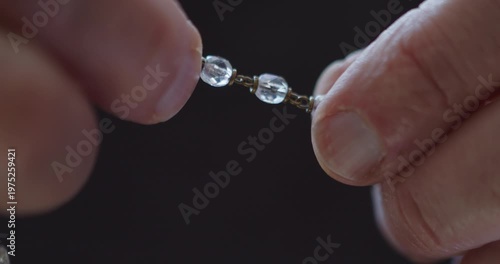 Extreme Close-up of fingers using rosary beads to pray
