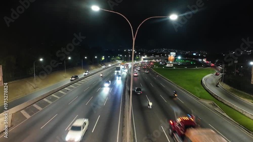 Real-time wide shot of vehicles driving through the main expressway of Caracas with city lights and mountains