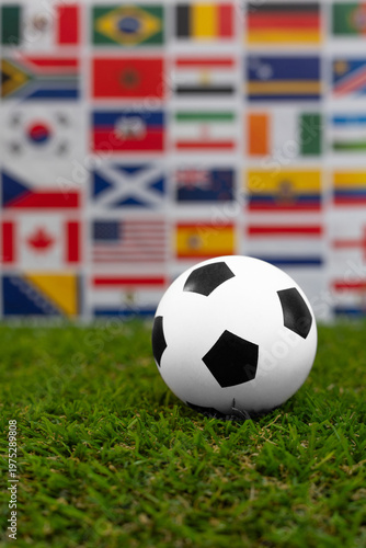 Soccer ball on green grass with blurred international flags in the background. Concept of world cup, global football tournament, international teams and world championship.