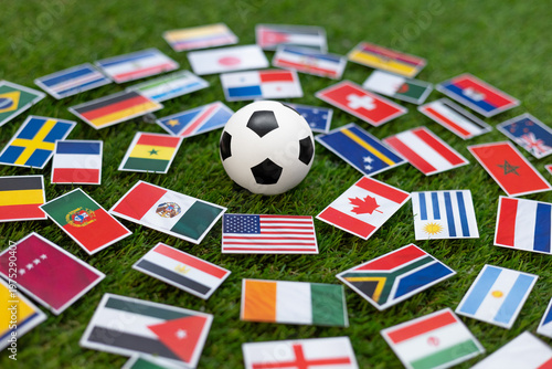 Fotografie Soccer ball on green grass surrounded by international flags arranged around it