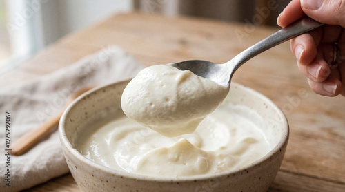 Spoon lifting thick creamy homemade yogurt