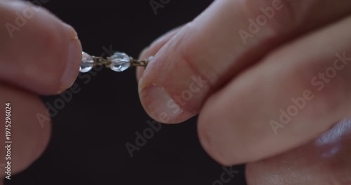 Extreme Close-up of fingers using rosary beads to pray
