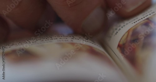 Extreme Close-up of a man's finger reading and scrolling through a prayer book

