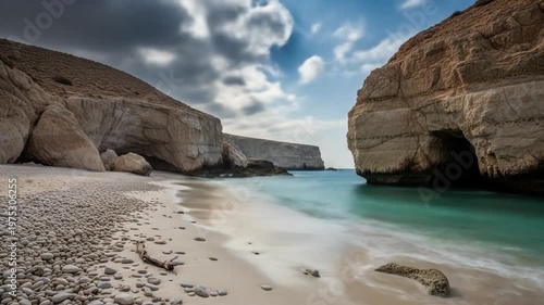 Coastal view with tan cliffs framing a beach Cloudy sky above turquoise water