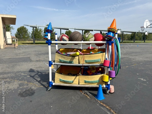Bilde på lerret Recess Play Equipment: A mobile cart filled with colorful balls, cones, and hoops on a blacktop field, ready for healthy outdoor play and exercise