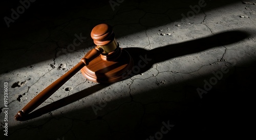 Judge gavel casting strong shadow on textured surface with high contrast lighting. Abstract legal concept representing justice, authority, decision making, and courtroom power.