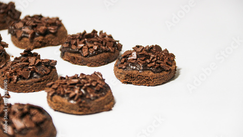 Delicious chocolate cake topped with chocolate chunks, on a white background. Freshly baked chocolate cake with a rich cocoa texture and chocolate shavings.