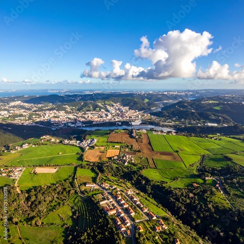 Aerial View of Lush Green Fields and Coastal City Under a Blue Sky.