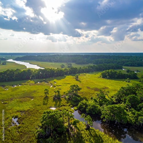 Aerial View of Lush Green Landscape with River and Cloudy Sky.