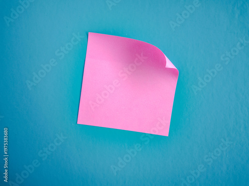 Minimalist Pink Square Sticky Note with Curled Corner on Blue Textured Background - Top View with Copy Space