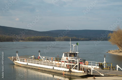 The river ferry from two connected sections: a flat transport barge and push boat (pusher tug) attached at the rear docked by the Shore