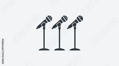 Three Microphones on Stands Against a Gray Background