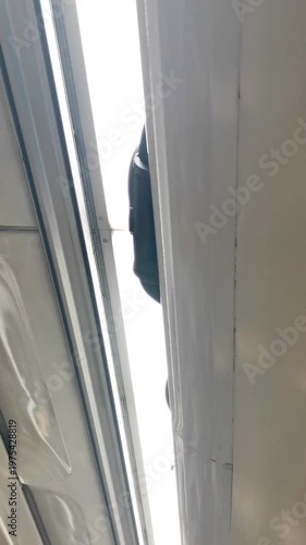 Person placing suitcase into overhead luggage compartment during travel