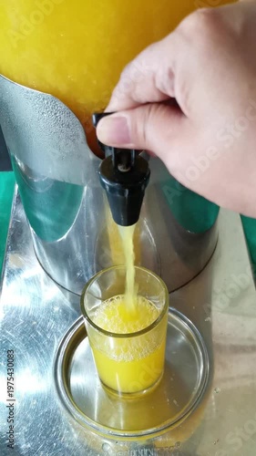 Fresh Orange Juice Being Poured from a Cold Beverage Dispenser into a Glass