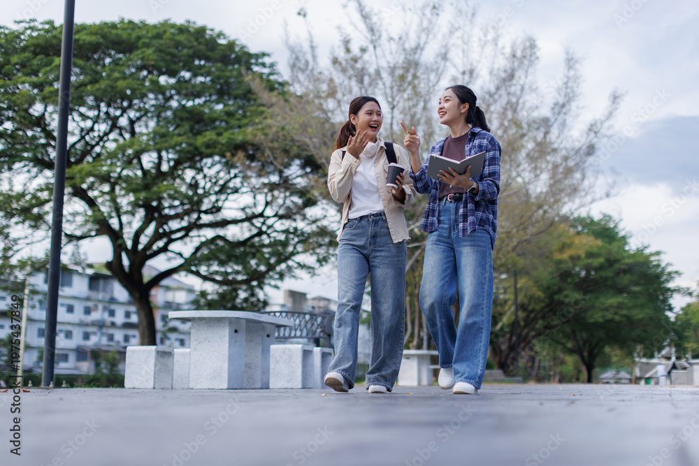 Obraz premium Asian college students walking and chatting in park