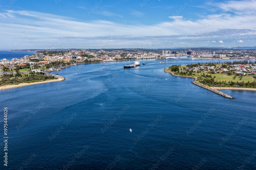 Fototapeta premium Aerial drone view of a large cargo ship being escorted by tug boats through Newcastle Harbour in New South Wales, Australia.