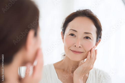 鏡で肌の状態をチェックする日本人女性（スキンケア・美容意識）｜Japanese woman checking skin condition in mirror
