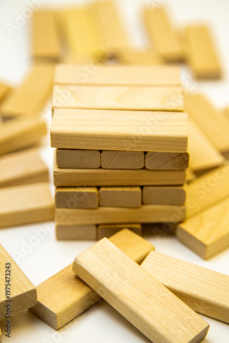A tower of wooden bars stands in the center of scattered bars on a white background. Concept of construction, wooden houses, mortgage, investment, wood. High quality photo