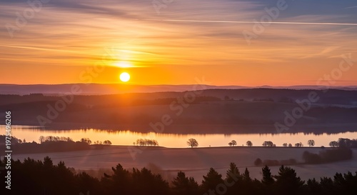 Beautiful sunrise over a misty lake and forest landscape.