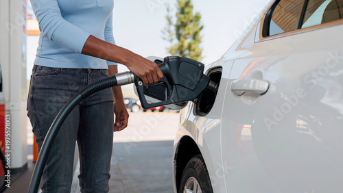 filling gas tank, The person is prepared for a journey, The car is ready for the road, The nozzle trigger is being pressed, The scene is shot from a side angle, This is a routine stop for fuel