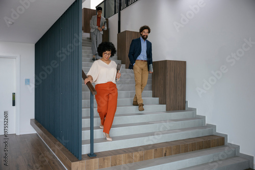 Business team walking down modern staircase in office building