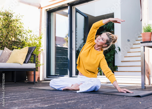 Woman practicing yoga and stretching outside on terrace in summer