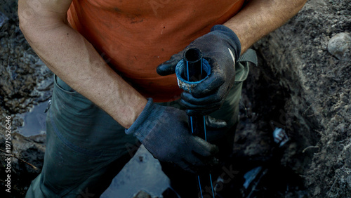 Bild auf Leinwand Worker installing plastic pipe connector onto irrigation line inside dug trench,