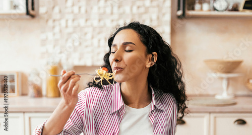 Принти на полотні A woman is sitting at a kitchen table with a plate of pasta in front of her