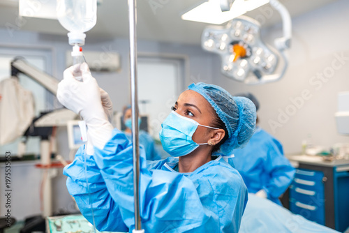 Quadro su tela Female nurse or doctor adjusting IV drip infusion in operating room