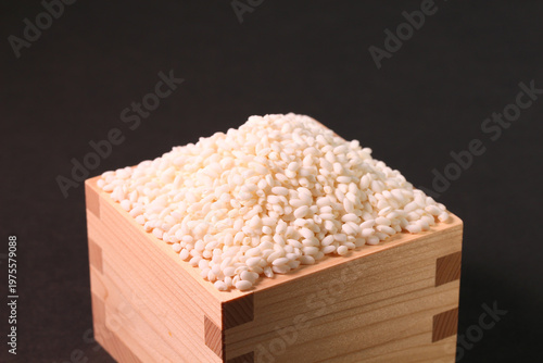 黒背景の枡に山盛りに盛られた真っ白なもち米