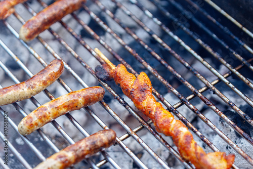 Grilling sausages and pork skewers on charcoal barbecue