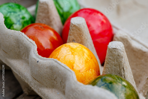 Colorful dyed easter eggs sitting in a cardboard carton