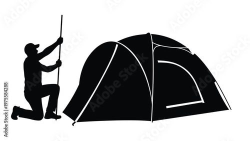 Silhouette of a man kneeling while setting up a camping tent for an outdoor wilderness trip