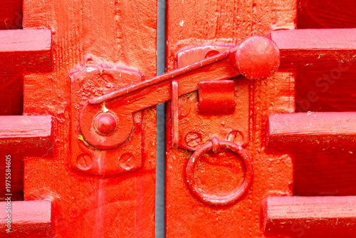 Red wooden shutter showing metal latch and ring handle