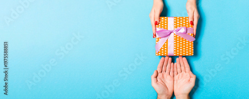 Fotografie Top view of couple giving and receiving a gift on colorful background