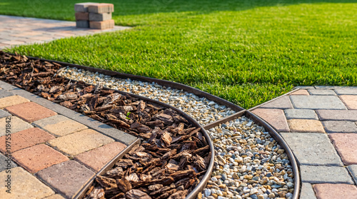 Photos Curved garden borders neatly separating patio pavers, bark mulch, decorative pebbles, and lush green grass