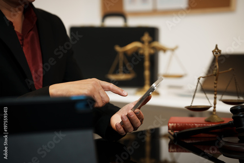Businessman in office using smartphone beside gavel and scales of justice, legal consultation and law firm concept with copy space.