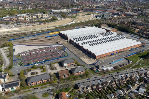 Aerial view of industrial rail depot in the city of York in the UK with warehouse buildings solar panels train tracks and nearby housing under a bright sky showing mixed urban and industrial land use